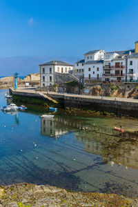 Buildings by river against clear sky