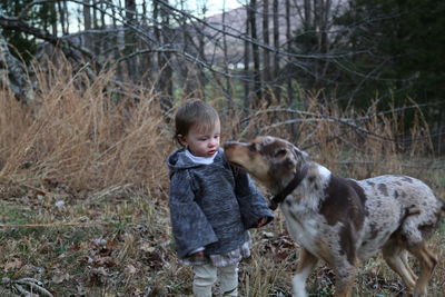 Dog by girl standing on field