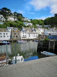 Sailboats moored in river by buildings against sky