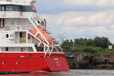 Red boat in river against sky