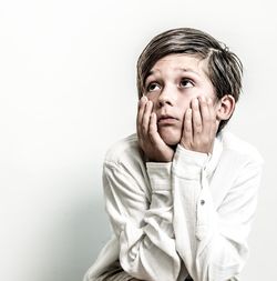 Boy looking away against white background