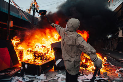 Man throwing cap in fire on street