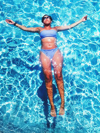 Full body shot of young woman floating in a swimming pool 
