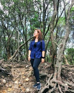 Woman standing on tree trunk in forest