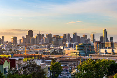 Modern buildings in city against sky during sunset