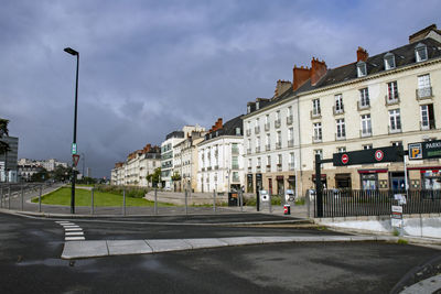 Street by buildings against sky in city