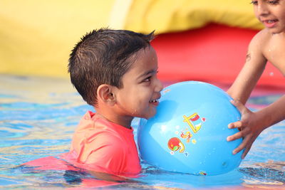 Side view of boy playing with friend in swimming pool