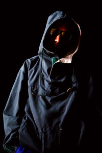 Close-up of man wearing mask against black background