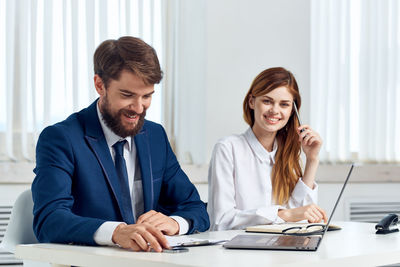 Portrait of smiling young couple sitting on table