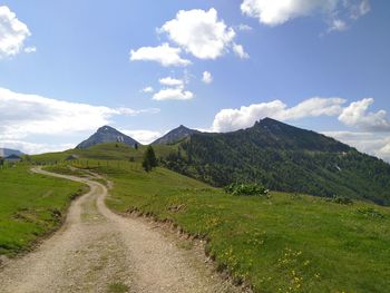 Scenic view of road by mountains against sky