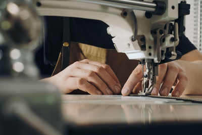 Tailor sewing at workplace. man hands sewing on machine at his studio. tailoring concept. close-up