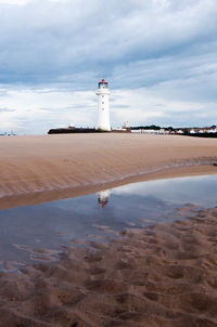 Lighthouse on beach against sky