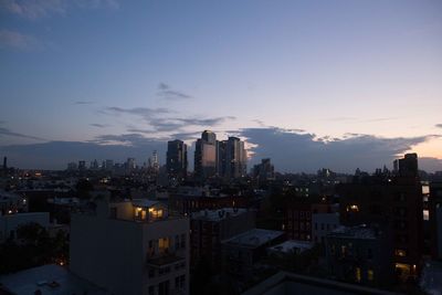 Illuminated city buildings against sky during sunset