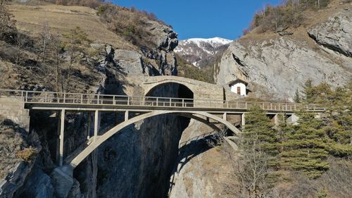 Arch bridge over river amidst buildings against sky