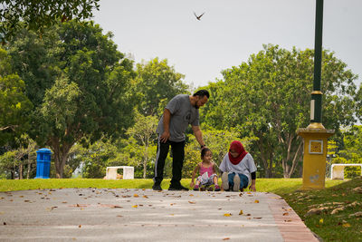 Children riding skateboard and scooter in the park.