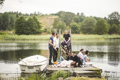 Happy friends enjoying on jetty over lake during weekend getaway