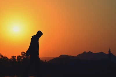 Silhouette man standing against sky during sunset