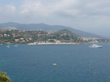 Boats in sea against cloudy sky