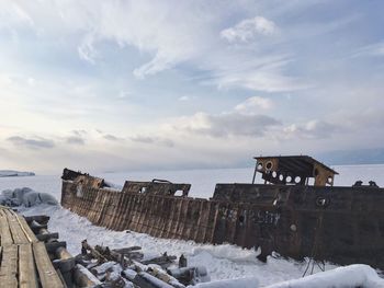 Buildings by houses against sky during winter