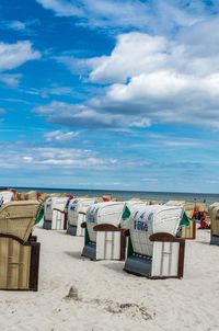 Hooded chairs at beach against sky