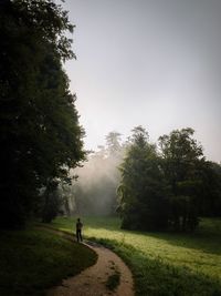 Man walking on golf course against sky