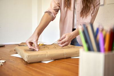 Midsection of woman working on table at home