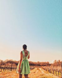 Rear view of woman standing on field against sky