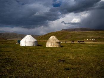 Scenic view of field  and yurts against sky