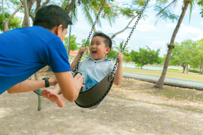 Laughing boy playing at playground with father