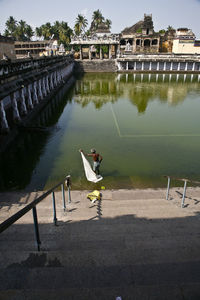 Reflection of man on railing by lake