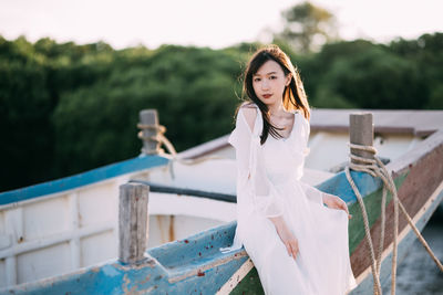 Portrait of young woman standing against railing