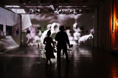 Rear view of people walking in illuminated building