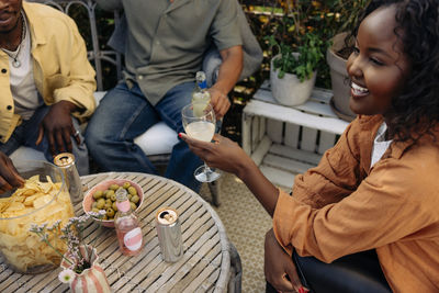 High angle view of smiling woman enjoying drinks with friends during dinner party