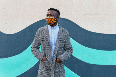 Man with umbrella standing against wall