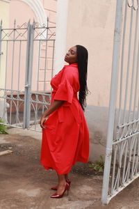 Smiling young woman looking away while standing by gate