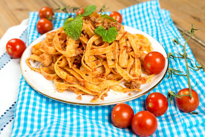 Close-up of tagliatelle pasta amidst tomatoes on table