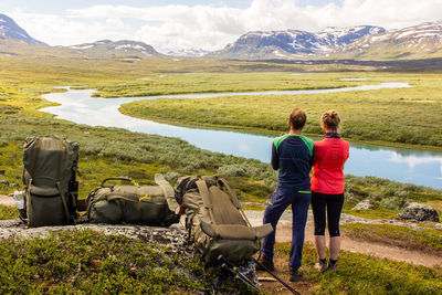 Rear view of people looking at lake against mountain