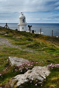 Lighthouse by sea against sky