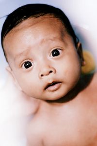 Close-up portrait of shirtless cute baby boy in bathtub