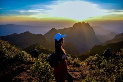 Female hiker standing on mountain against sky during sunset