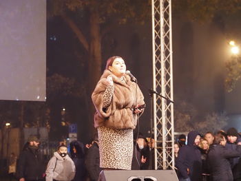 People looking at illuminated sculpture in city at night