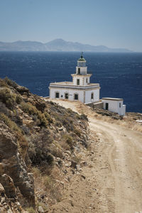 Lighthouse by sea against sky