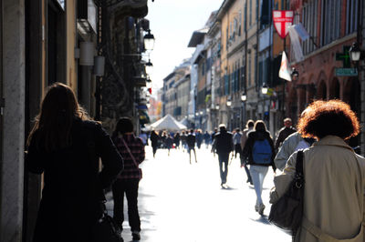Pedestrians walking on city street amidst buildings in italy.