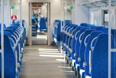 Interior of modern passenger high-speed express train, row of empty blue fabric soft seats.