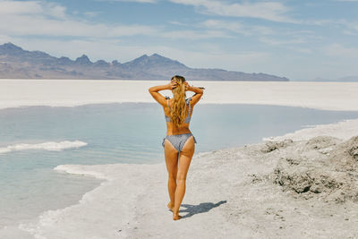 Woman standing at beach against sky