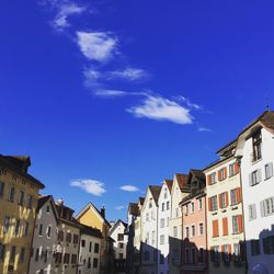 Low angle view of buildings in town against blue sky