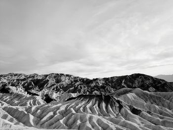 View of sand dunes against cloudy sky