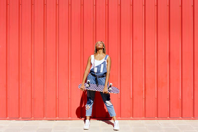 Portrait of young woman standing against yellow wall