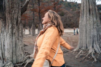 Side view of woman standing on tree trunk