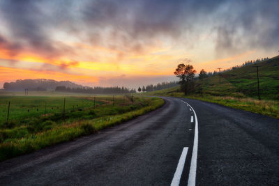 Empty road along landscape at sunset